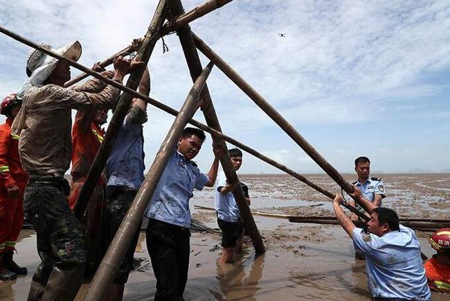 7月6日，救援人员在海滩上搭建临时遮阳棚。